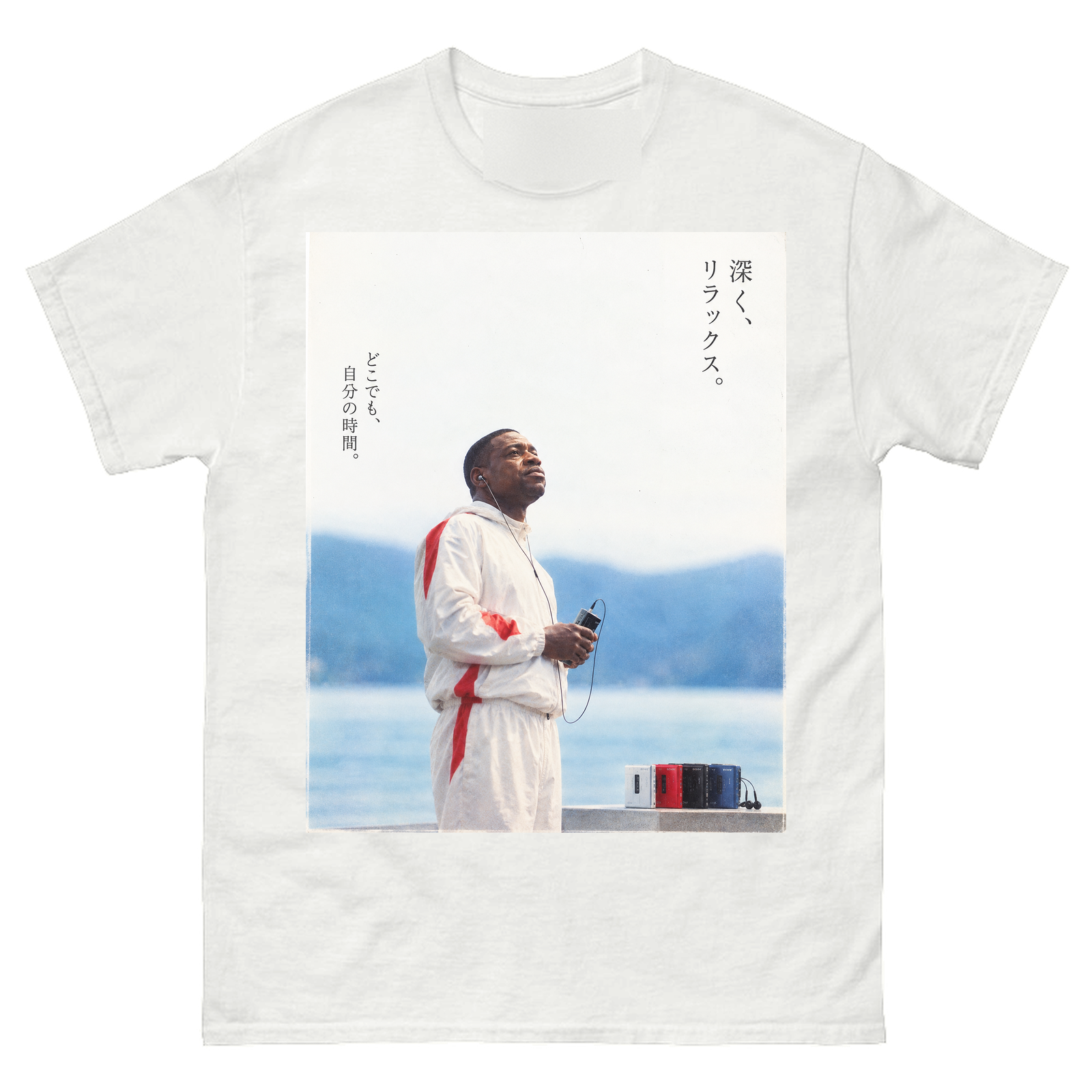 White tee with a large photograph on the front of a man in a white and red tracksuit holding a cassette player and looking up at the sky beside a blue lake and mountains